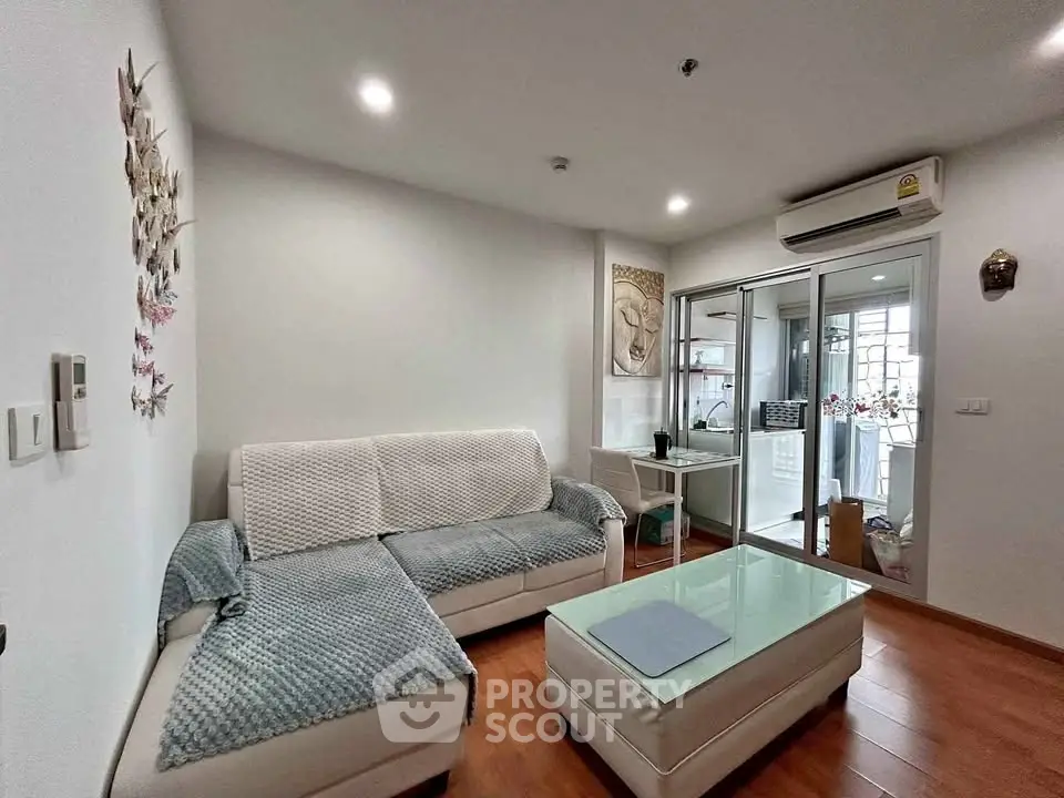 Modern living room with cozy seating and glass coffee table, featuring a bright and inviting atmosphere.