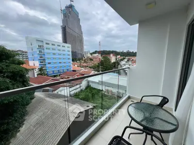 Modern balcony with glass railing offering cityscape views, perfect for relaxation.