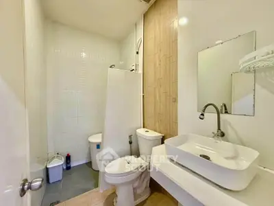 Modern bathroom with sleek fixtures and minimalist design, featuring a spacious shower and elegant sink.
