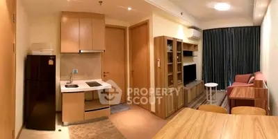 Modern apartment interior with open kitchen and cozy living area, featuring wooden cabinetry and contemporary furnishings.