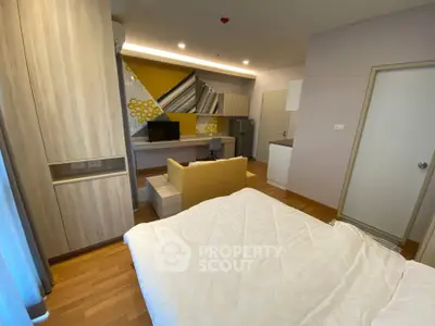 Modern bedroom with stylish decor and cozy ambiance, featuring a small living area and kitchenette.