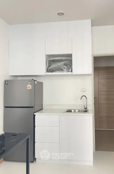 Modern compact kitchen with sleek white cabinetry and stainless steel appliances.