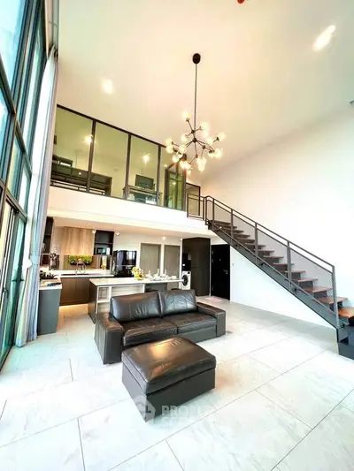 Stunning modern loft with high ceilings, open kitchen, and stylish staircase in a bright living area.