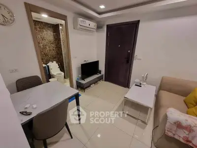 Cozy living room with modern decor and open view to bathroom, featuring a compact TV setup and air conditioning.