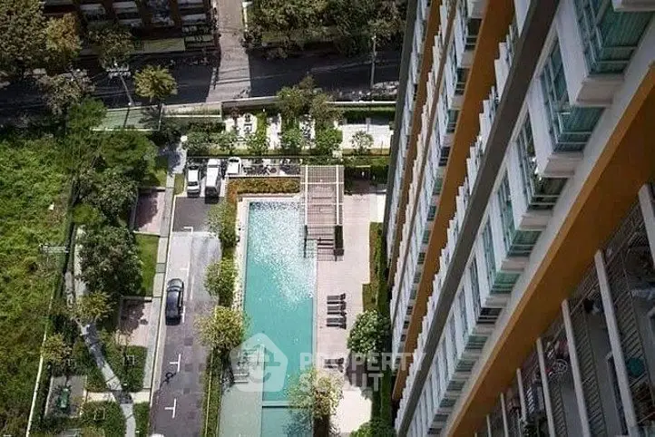 Stunning aerial view of modern apartment building with pool and lush greenery, perfect for urban living.