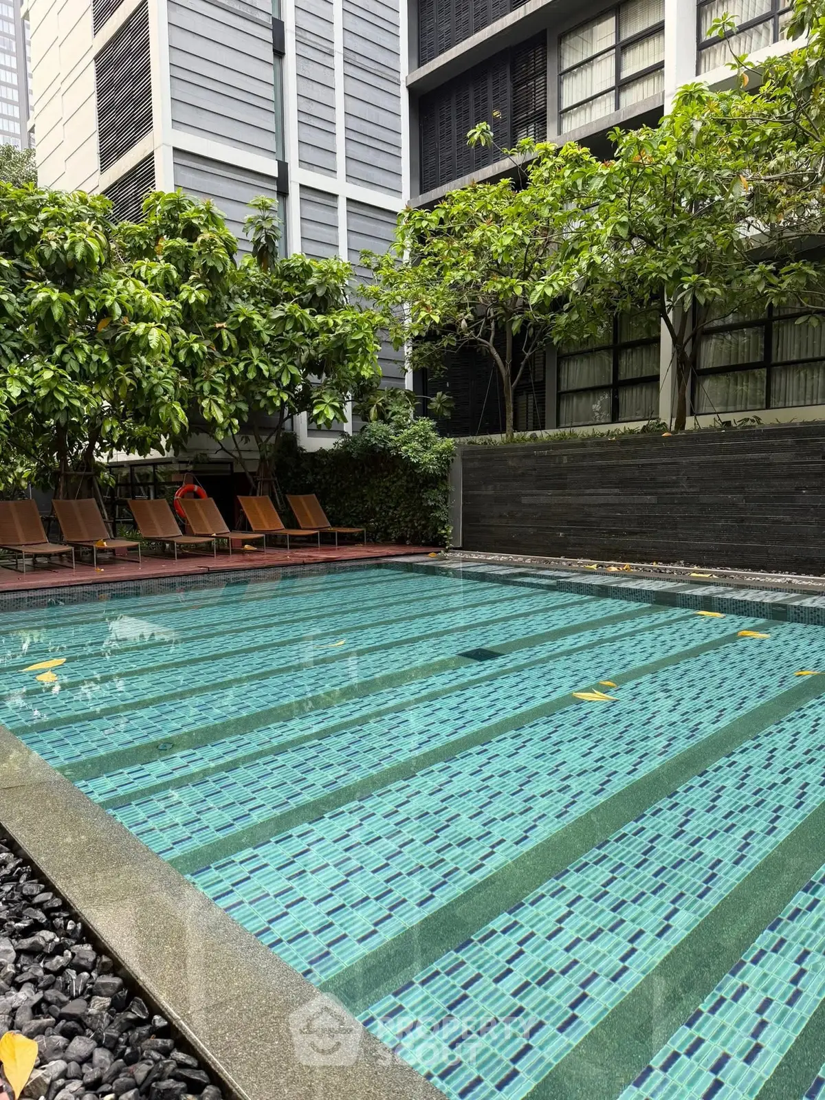 Luxurious apartment complex with serene outdoor pool and lush greenery, perfect for relaxation and leisure.