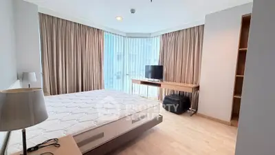 Spacious bedroom with large windows and modern furnishings in a high-rise apartment.