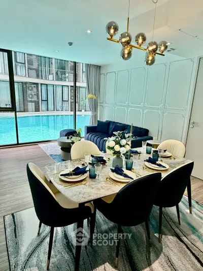 Luxurious living room with pool view, elegant dining setup, and modern lighting