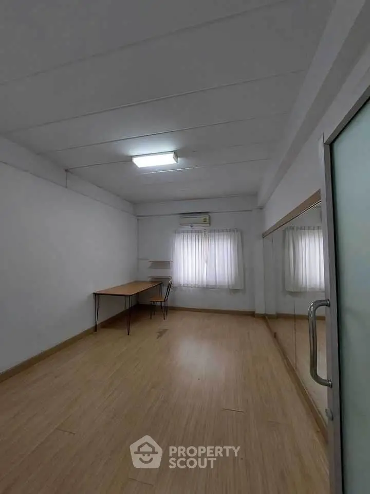 Spacious study room with wooden flooring and natural light, perfect for productivity.