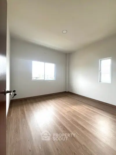 Spacious empty bedroom with wooden flooring and natural light