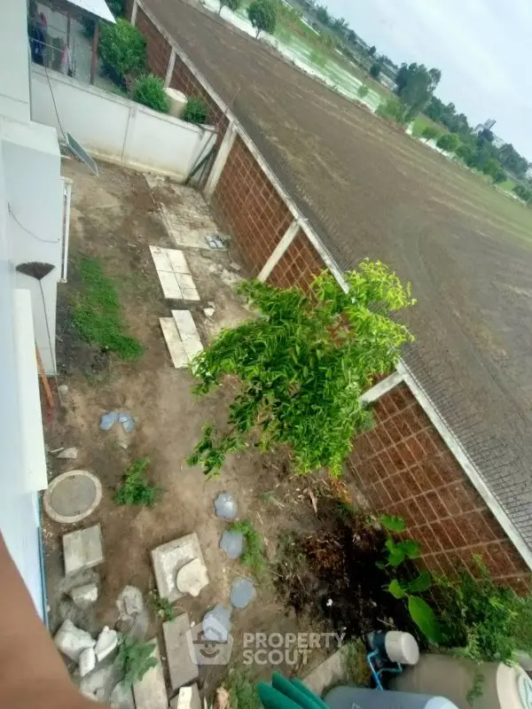 Aerial view of a backyard garden with potential for landscaping, adjacent to open fields.
