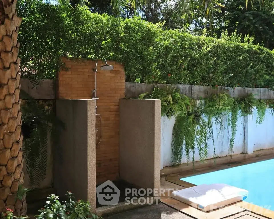 Luxurious outdoor pool area with shower and lush greenery for a serene retreat.