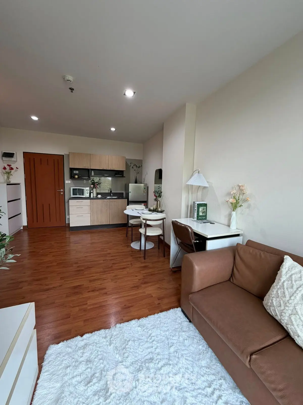 Modern living room with open kitchen, cozy seating, and elegant decor in a stylish apartment.