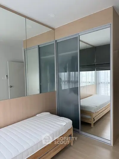 Modern bedroom with mirrored wardrobe and single bed in sleek apartment.