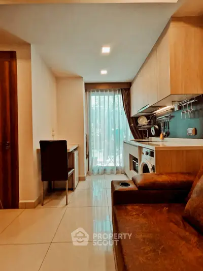 Cozy living room with modern kitchen and washing machine, perfect for urban living.