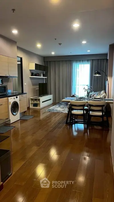 Modern open-plan living room with kitchen, featuring hardwood floors and stylish furnishings.