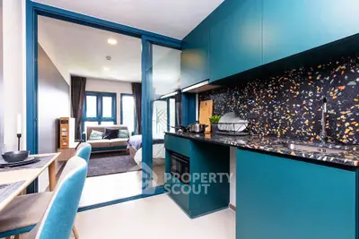 Modern open-layout kitchen with stylish blue cabinets and terrazzo backsplash leading to a cozy living area.