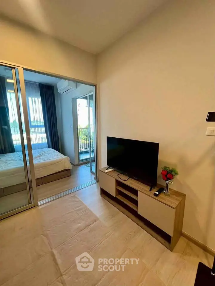 Modern living room with TV and view into cozy bedroom