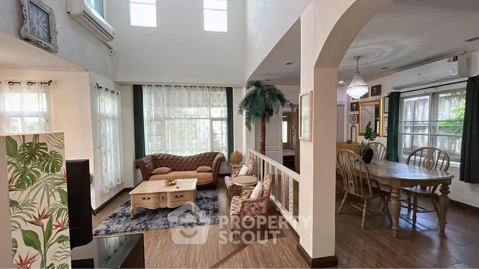Spacious living room with elegant decor and dining area, featuring high ceilings and abundant natural light.