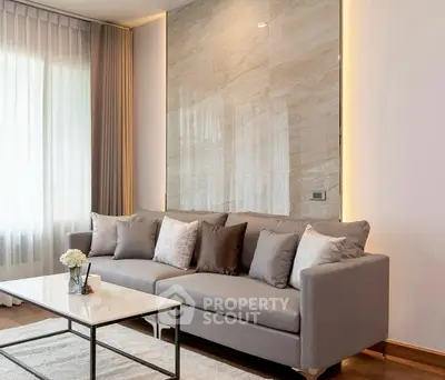 Elegant living room with modern gray sofa and marble accent wall, perfect for stylish urban living.