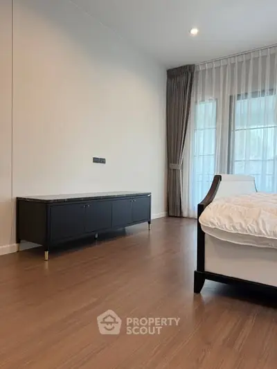 Spacious bedroom with elegant wooden flooring and modern furniture