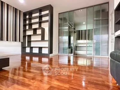 Spacious modern living room with sleek wooden flooring and built-in shelving