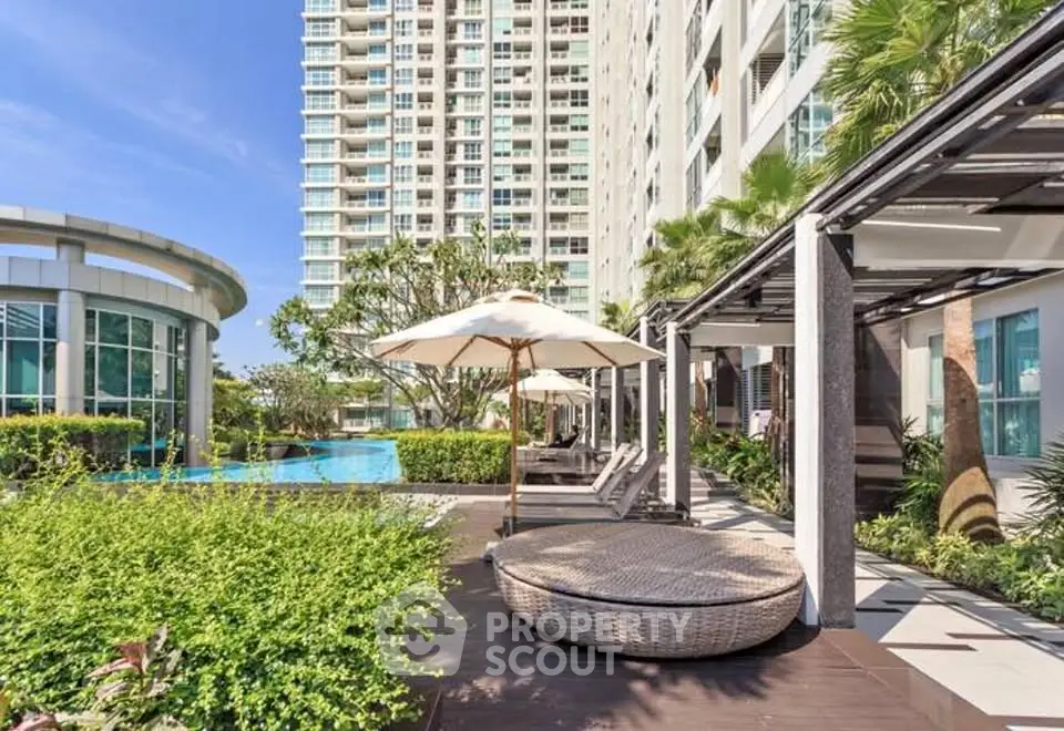 Luxurious apartment complex with poolside relaxation area and modern architecture.
