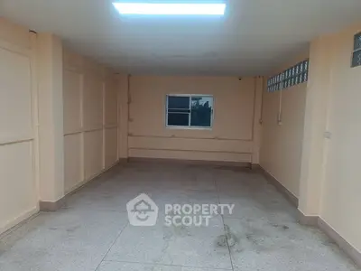 Spacious empty room with window and tiled floor, ideal for storage or garage use.