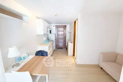 Modern minimalist apartment interior with compact kitchen and cozy seating area.