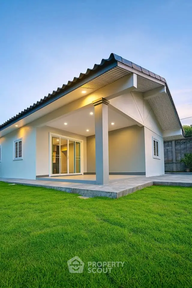 Modern single-story home with spacious lawn and elegant exterior lighting.