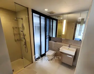 Modern bathroom with glass shower and sleek fixtures in luxury apartment.