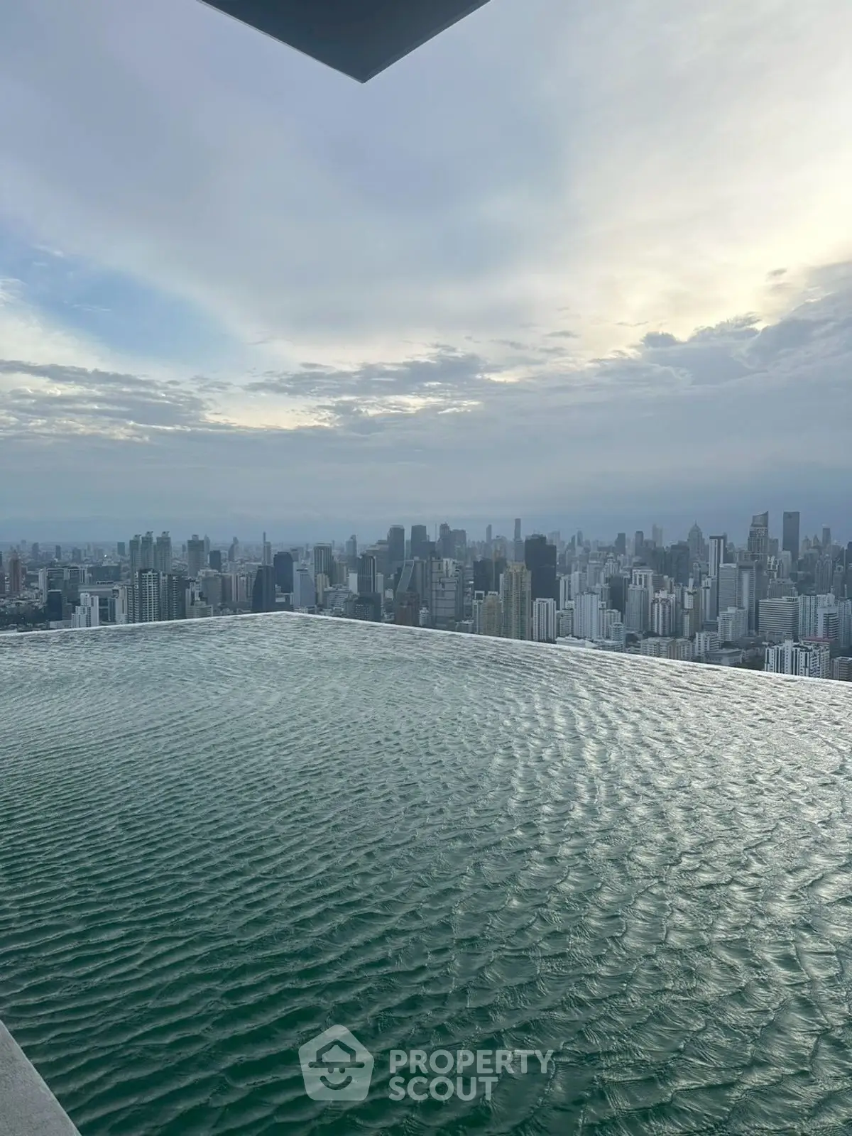 Stunning rooftop infinity pool with breathtaking city skyline view at sunset.