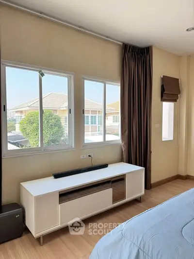 Bright bedroom with large windows and modern furniture in a cozy home setting.