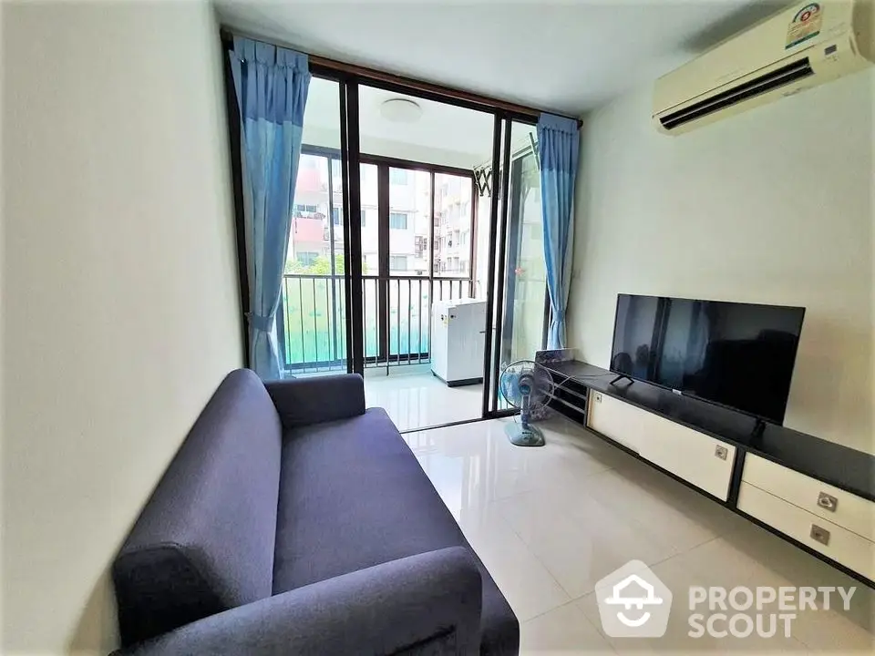 Modern living room with balcony, featuring sleek furniture and air conditioning.