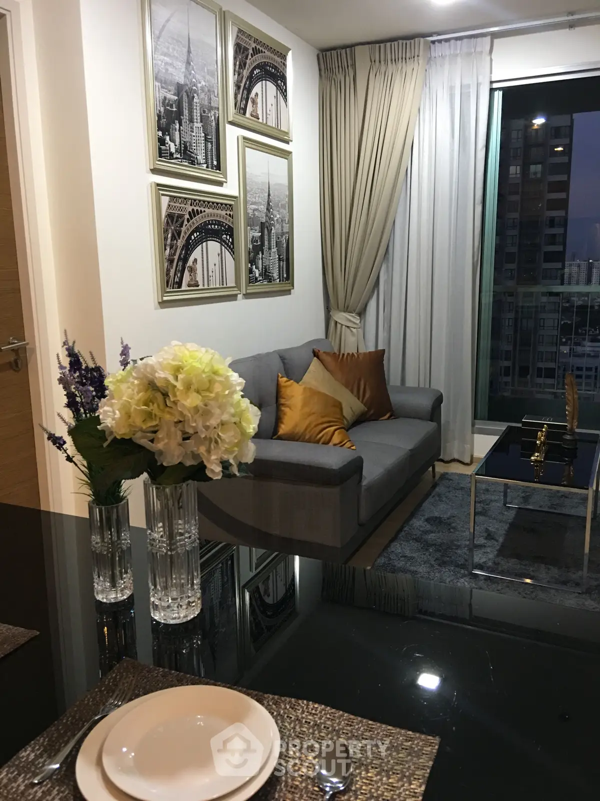 Modern living room with elegant decor and city view, featuring a cozy sofa and stylish artwork.