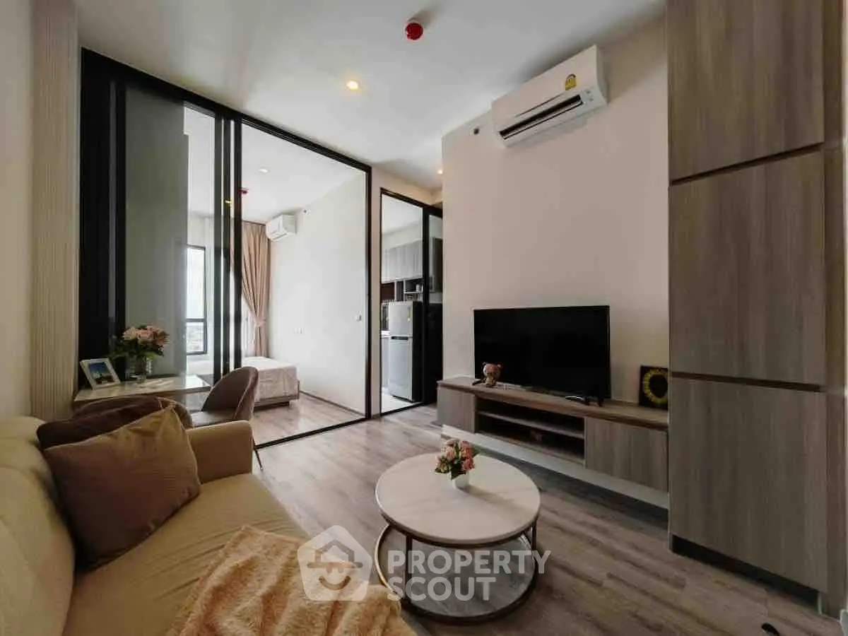 Modern living room with sleek design and open layout, featuring a cozy sofa and flat-screen TV.
