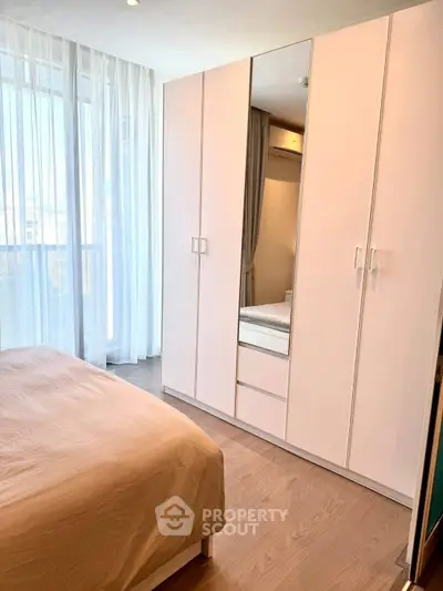 Bright bedroom with large wardrobe and floor-to-ceiling windows in modern apartment.