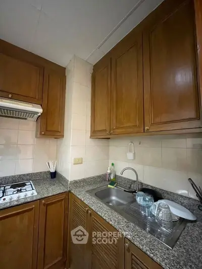 Cozy kitchen with wooden cabinets and granite countertops, featuring a gas stove and stainless steel sink.
