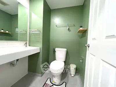 Modern bathroom with green walls, sleek fixtures, and minimalist decor