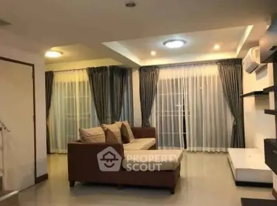 Spacious living room with modern sofa and elegant curtains in a well-lit interior.