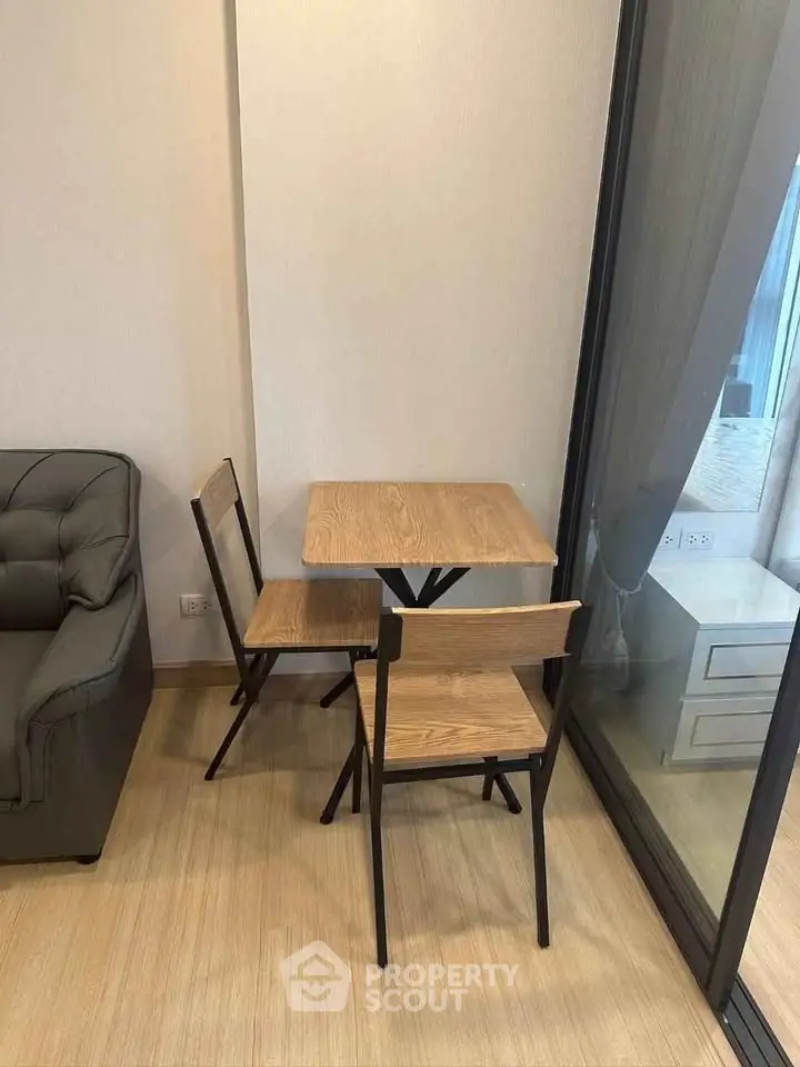 Cozy corner with wooden table and chairs next to a glass partition in a modern apartment.