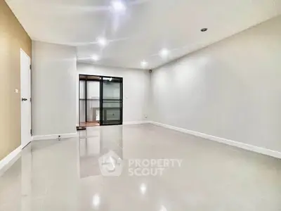 Spacious empty living room with glossy tiled floors and modern lighting.