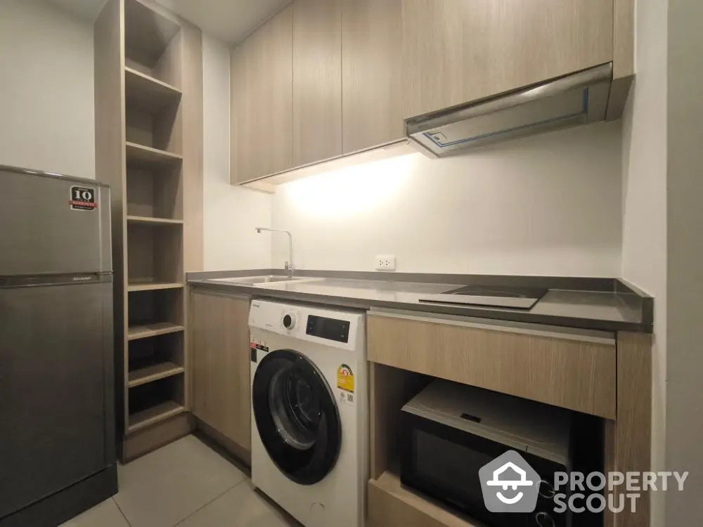 Modern kitchen with washing machine, microwave, and sleek cabinetry