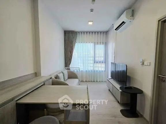Modern living room with sleek furniture and large window, featuring air conditioning and a flat-screen TV.