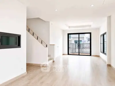 Spacious modern living room with wooden flooring and large windows for natural light.