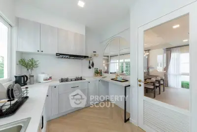 Modern kitchen with open layout and gas stove, featuring sleek cabinetry and natural light.