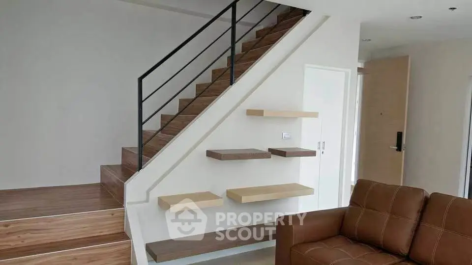 Modern interior with stylish staircase and cozy brown sofa in a contemporary living room.