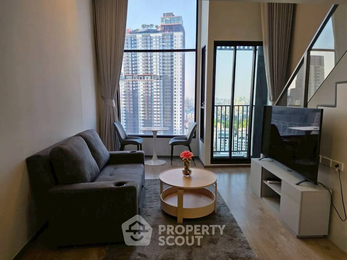 Modern living room with city view, featuring sleek furniture and floor-to-ceiling windows.