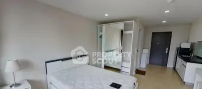 Modern bedroom with mirrored wardrobe and compact kitchen area in a stylish apartment.