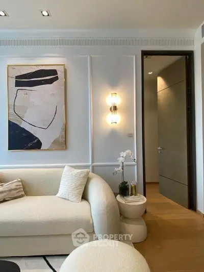 Elegant living room with modern art and plush sofa, featuring stylish lighting and wooden flooring.